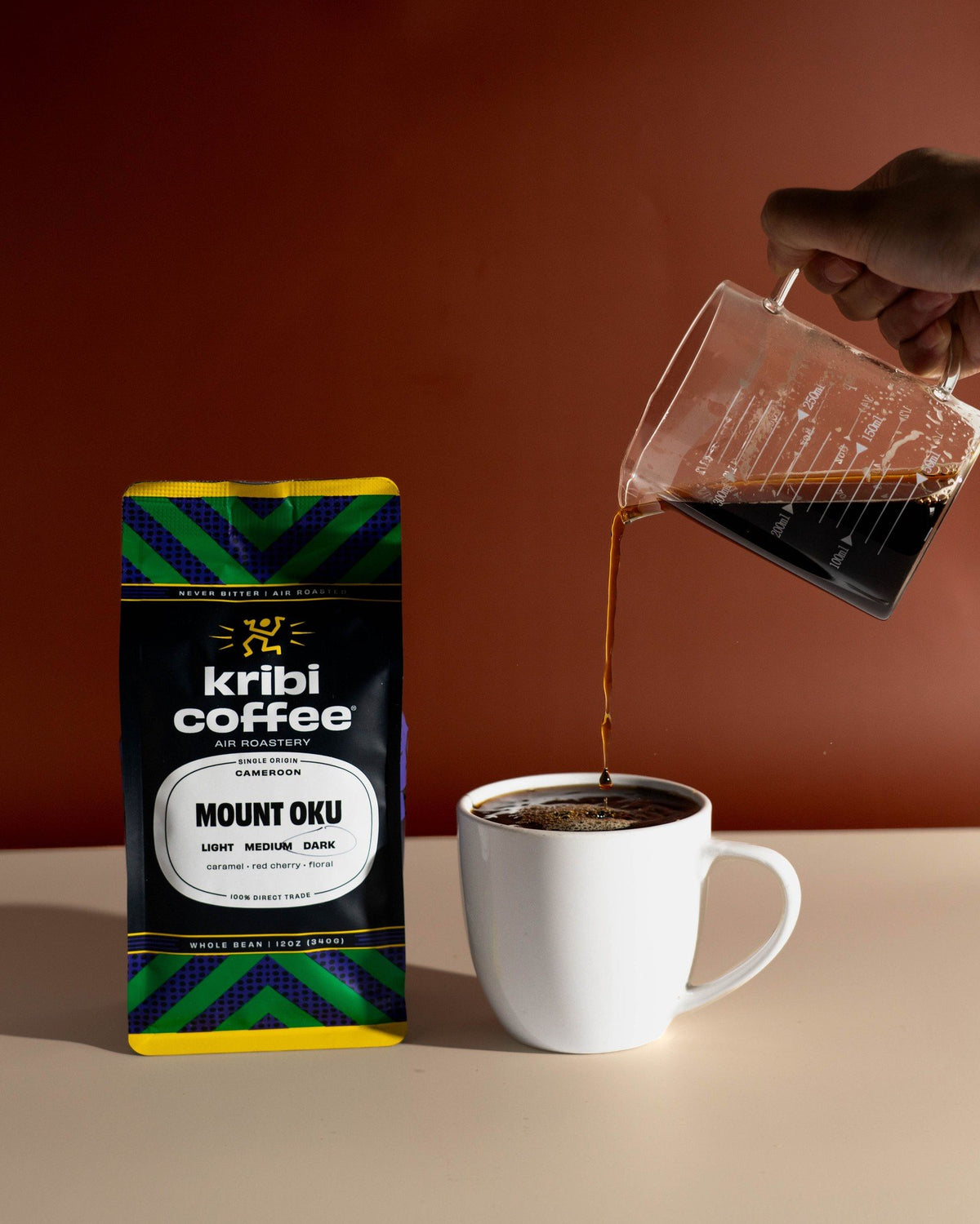 Drip coffee poured into a white mug next to a bag of Mount Oku