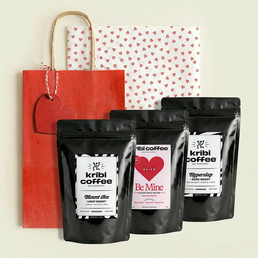 Three black kribi coffee bags with heart designs on a red bag with a heart tag.