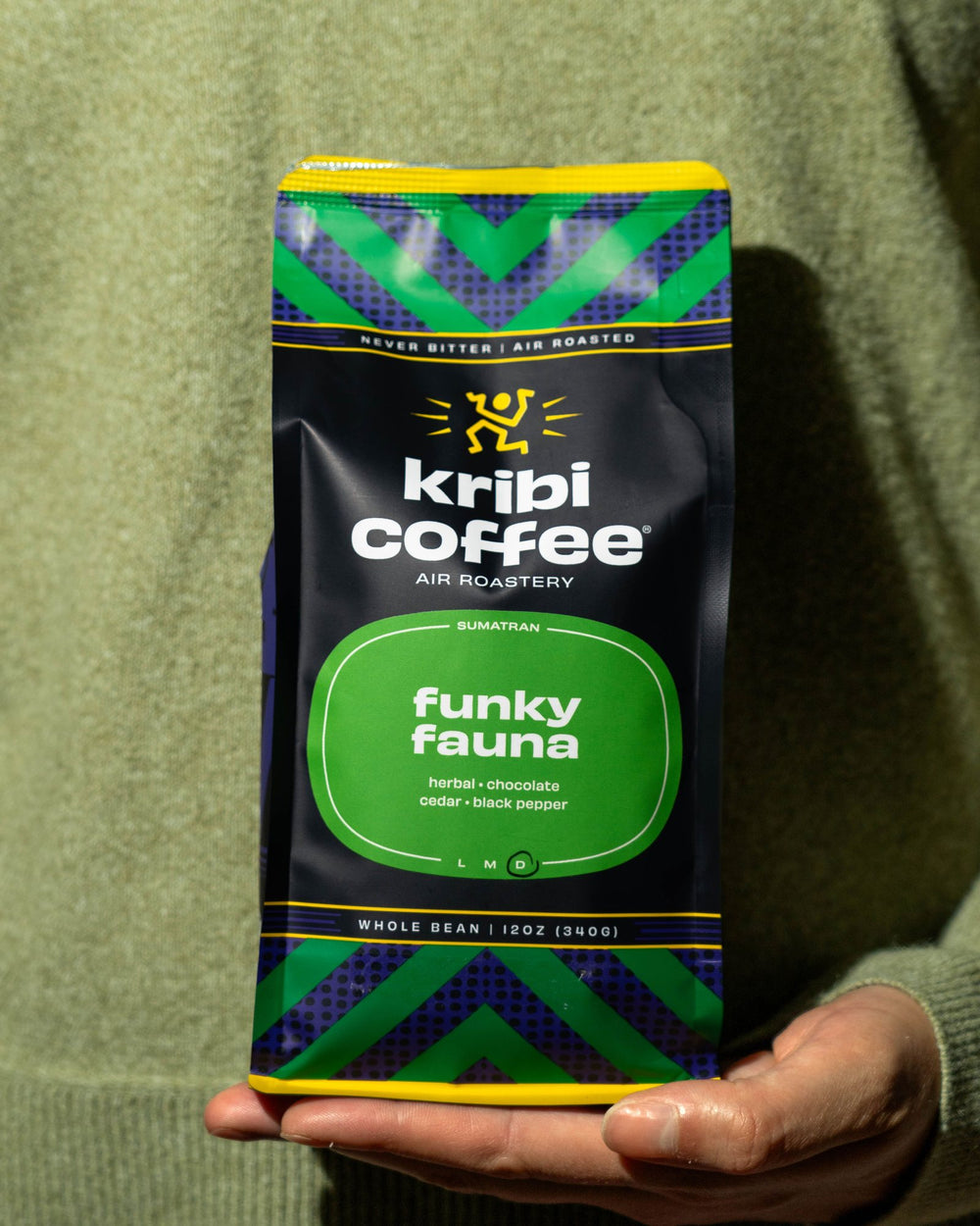 A hand holding out a bag of Funky Fauna coffee