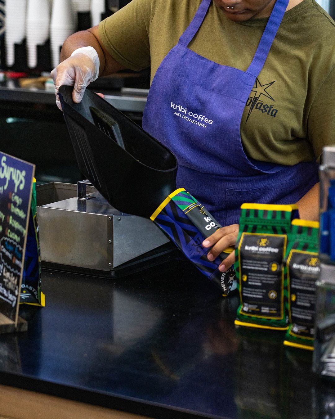 A barista ringing up bags of Kribi Coffee at the Oak Park counter